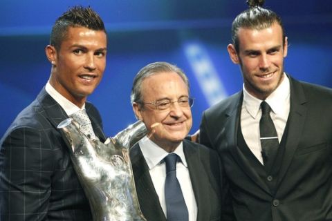 Real Madrid's forward Cristiano Ronaldo of Portugal, left, holds his "best player of the year" trophy, as he poses with Real Madrid's forward Gareth Bale, right, who was nominated for the same award, and Real Madrid's president Florentino Perez, during the UEFA Champions League draw, at the Grimaldi Forum, in Monaco, Thursday, Aug. 25, 2016. (AP Photo/Claude Paris)
