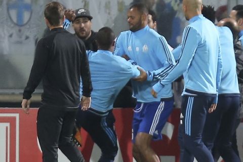 Marseille's Patrice Evra, third left, raises his foot trying to kick a man during a scuffle with Marseille supporters who trespassed into the field before the Europa League group I soccer match between Vitoria SC and Olympique de Marseille at the D. Afonso Henriques stadium in Guimaraes, Portugal, Thursday, Nov. 2, 2017. Evra was shown a red card before the start of the match for his involvement in the incident. (AP Photo/Luis Vieira)