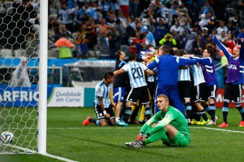 SAO PAULO, BRAZIL - JULY 09:  Jasper Cillessen of the Netherlands sits on the pitch after failing to save the penalty kick of Maxi Rodriguez of Argentina as Argentina celebrate during the 2014 FIFA World Cup Brazil Semi Final match between the Netherlands and Argentina at Arena de Sao Paulo on July 9, 2014 in Sao Paulo, Brazil.  (Photo by Clive Rose/Getty Images)