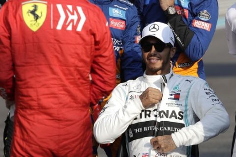 Mercedes driver Lewis Hamilton of Britain, right, looks to the Ferrari driver Sebastian Vettel of Germany, flanked by his teammate Valtteri Bottas of Finland, right, during the end season driver's picture at the Emirates Formula One Grand Prix, at the Yas Marina racetrack in Abu Dhabi, United Arab Emirates, Sunday, Dec.1, 2019. (AP Photo/Luca Bruno)