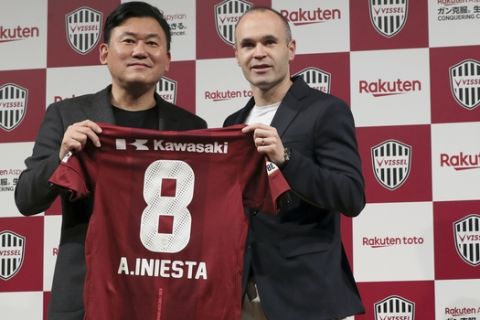 Former Barcelona player Andres Iniesta, right, holds his new uniform with Hiroshi Mikitani, left, owner of Vissel Kobe, during a press conference announcing Iniesta move to Japan's Vissel Kobe in Tokyo Thursday, May 24, 2018. (AP Photo/Eugene Hoshiko)