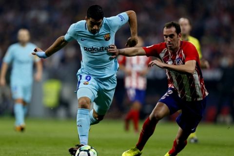 Barcelona's Luis Suarez, left, vies for the ball with Atletico Madrid's Diego Godin during a Spanish La Liga soccer match between Atletico Madrid and Barcelona at the Metropolitano stadium in Madrid, Saturday, Oct. 14, 2017. (AP Photo/Francisco Seco)