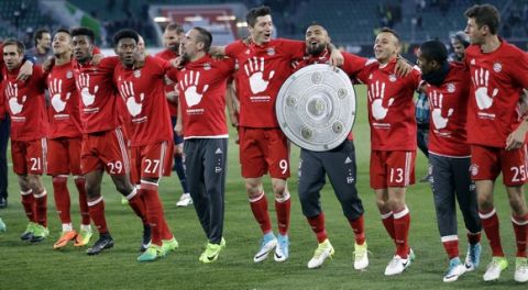 Bayern's Arturo Vidal carries a mock trophy as he and his teammates celebrate winning the German soccer champion title after the Bundesliga soccer match against VfL Wolfsburg in Wolfsburg, Germany, Saturday, April 29, 2017. (AP Photo/Michael Sohn)