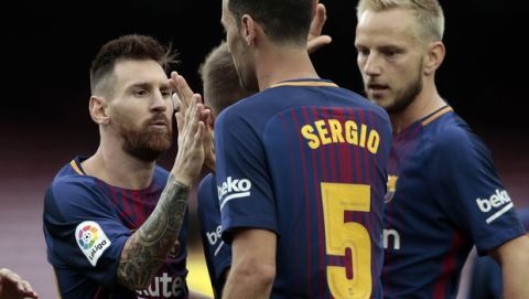 Barcelona's Lionel Messi, left, celebrates a goal with Barcelona's Sergio, center, during the Spanish La Liga soccer match between Barcelona and Las Palmas at the Camp Nou stadium in Barcelona, Spain, Sunday, Oct. 1, 2017. Barcelona's Spanish league game against Las Palmas is played without fans amid the controversial referendum on Catalonia's independence. (AP Photo/Manu Fernandez)