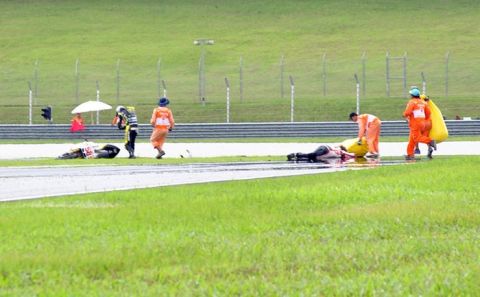 Race marshalls attend to Honda rider Marco Simoncelli (centre R) of Italy following a fatal crash four minutes after the start of the Malaysian MotoGP race in Sepang on October 23, 2011. Simoncelli died of injuries sustained in the crash that resulted in the cancellation of the Malaysian MotoGP, in the latest tragedy to hit motor sports. The crash occurred just minutes after the race began when the 24-year-old Honda rider's bike veered across the track and into the path of riders Colin Edwards and Valentino Rossi. AFP PHOTO (Photo credit should read STR/AFP/Getty Images)