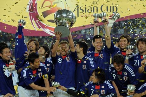 Japanese players celebrate as midfielder Keisuke Honda (C) holds their 2011 Asian Cup trophy after winning the final football match against Australia at Khalifa Stadium in the Qatari capital Doha on January 29, 2011. Japan beat Australia 1-0 to win fourth Asian Cup title. AFP PHOTO/MANAN VATSYAYANA (Photo credit should read MANAN VATSYAYANA/AFP/Getty Images)