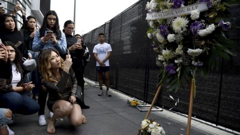 People gather near a makeshift memorial for former NBA basketball player Kobe Bryant outside of the Staples Center prior to the start of the 62nd annual Grammy Awards at the Staples Center on Sunday, Jan. 26, 2020, in Los Angeles. Bryant died Sunday in a helicopter crash near Calabasas, Calif. He was 41. (AP Photo/Chris Pizzello)
