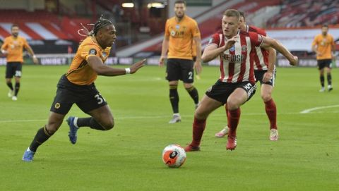 Wolverhampton Wanderers' Adama Traore, left, takes on Sheffield United's Jack O'Connell during the English Premier League soccer match between Sheffield United and Wolverhampton Wanderers at Bramall Lane stadium in Sheffield, England, Wednesday, July 8, 2020. (Peter Powell/Pool via AP)