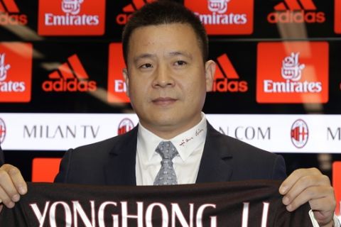 Chinese businessman Yonghong Li poses with an AC Milan jersey with his name during a press conference to illustrate takeover of AC Milan soccer club by a Chinese consortium, in Milan, Italy, Friday, April 14, 2017. A new era began at AC Milan on Thursday after the sale of Italy's most successful club to a Chinese-led consortium ended Silvio Berlusconi's 31 years in charge. (AP Photo/Antonio Calanni)