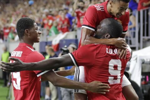Manchester United's Jesse Lingard, top, leaps into the arms of Romelu Lukaku, bottom, as Marcus Rashford, left, comes in to celebrate Lukaku's goal against Manchester City during the first half of an International Champions Cup soccer match in Houston, Thursday, July 20, 2017. (AP Photo/David J. Phillip)