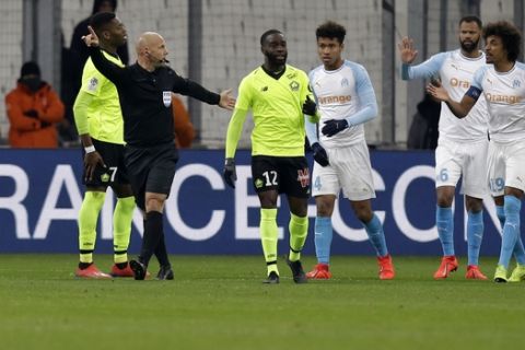 The referee stops play after a firecracker was thrown on the pitch during a French League One soccer match between Olympique Marseille and Lille at the Stade Velodrome in Marseille, France, Friday, Jan. 25, 2019. (AP Photo/Claude Paris)