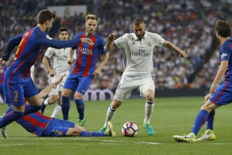 Real Madrid's Karim Benzema, center, tries to dribble pas Barcelona's Gerard Pique, left, Sergio Busquets, and Sergi Roberto, during a Spanish La Liga soccer match between Real Madrid and Barcelona, dubbed 'el clasico', at the Santiago Bernabeu stadium in Madrid, Spain, Sunday, April 23, 2017. (AP Photo/Francisco Seco)