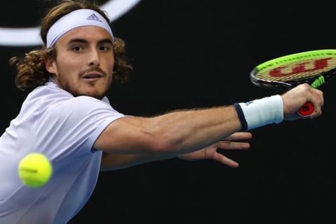 Greece's Stefanos Tsitsipas makes a backhand return to Canada's Milos Raonic during their third round singles match at the Australian Open tennis championship in Melbourne, Australia, Friday, Jan. 24, 2020. (AP Photo/Andy Wong)