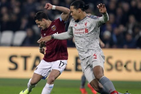 West Ham's Chicharito, left, and Liverpool's Virgil van Dijk challenge for the ball during the English Premier League soccer match between West Ham United and Liverpool at the London Stadium in London, Monday, Feb. 4, 2019.(AP Photo/Kirsty Wigglesworth)