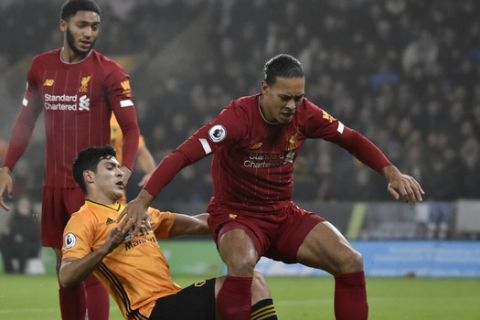 Liverpool's Virgil van Dijk, right, duels for the ball with Wolverhampton Wanderers' Raul Jimenez during the English Premier League soccer match between Wolverhampton Wanderers and Liverpool at the Molineux Stadium in Wolverhampton, England, Thursday, Jan. 23, 2020. (AP Photo/Rui Vieira)