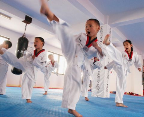 In this photo released by China's Xinhua News Agency, young  Chinese trainees practice Taekwondo in a Taekwondo training place in Suzhou, east China's Jiangsu Province, Tuesday,  July 18, 2006.  Children take part in various physical activities like Taekwondo and swimming in summer vacation. (AP Photo / Xinhua,  Hang Xingwei)                 
