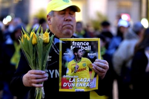 A FC Nantes soccer fan displays the cover of French soccer magazine, France Football, featuring FC Nantes soccer player Emiliano Sala of Argentina, during a tribute in Nantes, western France, Tuesday, Jan. 22, 2019. The French civil aviation authority said Tuesday, Emiliano Sala was aboard a small passenger plane that went missing off the coast of the island of Guernsey. (AP Photo/David Vincent)
