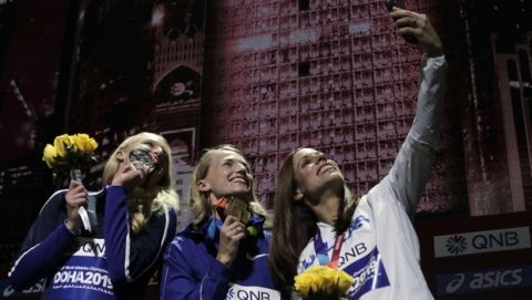 Medalists in the women's pole vault Anzhelika Sidorova, who participates as a neutral athlete, gold, center, Sandi Morris of the United States, silver, left, and Katerina Stefanidi of Greece, bronze, take a selfie during the medal ceremony at the World Athletics Championships in Doha, Qatar, Monday, Sept. 30, 2019. (AP Photo/Nariman El-Mofty)