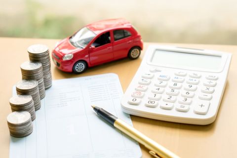 Coins stack in columns on saving book and car on finance concept