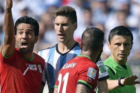 Iran's Masoud Shojaei and Ashkan Dejagah (21) argue with referee Milorad Mazic from Serbia during the group F World Cup soccer match between Argentina and Iran at the Mineirao Stadium in Belo Horizonte, Brazil, Saturday, June 21, 2014. (AP Photo/Martin Meissner)