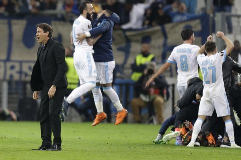 Marseille's head coach Rudi Garcia, left, reacts on the field while his players celebrate their 5-2 win over RB Leipzig at the end of the Europa League quarter final second leg soccer match at the Velodrome stadium in Marseille, southern France, Thursday, April 12, 2018. Marseille defeated Leipzig 5-2. (AP Photo/Claude Paris)