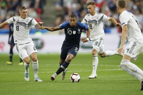 France's Kylian Mbappe, 2nd left, challenges for the ball with Germany's Toni Kroos, left, and Germany's Toni Kroos while Germany's Matthias Ginter, right, looks on during a UEFA Nations League soccer match between France and Germany at Stade de France stadium in Saint Denis, north of Paris, Tuesday, Oct. 16, 2018. (AP Photo/Christophe Ena)