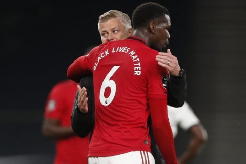 Manchester United's manager Ole Gunnar Solskjaer embraces Paul Pogba at the end of the English Premier League soccer match between Tottenham Hotspur and Manchester United at Tottenham Hotspur Stadium in London, England, Friday, June 19, 2020. (AP Photo/Matt Childs, Pool)