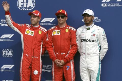 Ferrari driver Kimi Raikkonen of Finland, center, celebrates after setting a pole position with second placed Ferrari driver Sebastian Vettel of Germany, left, and third placed Mercedes driver Lewis Hamilton of Britain in the qualifying session at the Monza racetrack, in Monza, Italy, Saturday, Sept. 1, 2018. The Formula One race will be held on Sunday. (AP Photo/Luca Bruno)