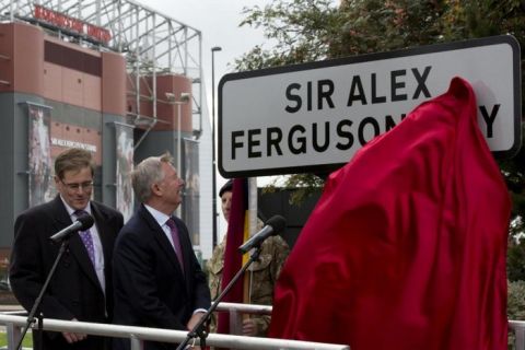 Manchester United's former manager Alex Ferguson, second left, stands alongside leader of Trafford Council Matthew College as he unveils a street named after him near Old Trafford Stadium, Manchester, England, Monday Oct. 14, 2013. Earlier in the day the side's manager for over 26 years was awarded the Honorary Freedom of the Borough of Trafford. (AP Photo/Jon Super)