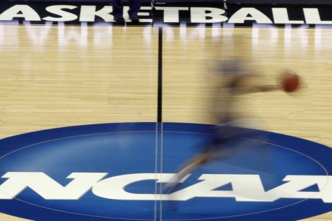 FILE - In this March 14, 2012, file photo, a player runs across the NCAA logo during practice in Pittsburgh before an NCAA tournament college basketball game. A federal probe illuminates a shady side of college basketball recruiting filled with bribes and kickbacks. Paying players has become standard operating procedure for some programs and the arrest of 10 people accused of influencing top recruits could change that. (AP Photo/Keith Srakocic, File)