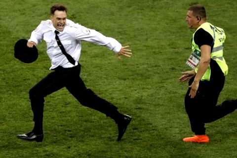 FILE - In this Sunday, July 15, 2018 file photo, Pyotr Verzilov invading the pitch, runs away as a steward tries to stop him during the France and Croatia 2018 World Cup final match in the Luzhniki Stadium in Moscow, Russia. Russian news reports say Verzilov a member of Russian punk protest group Pussy Riot has been hospitalized in grave condition for what could be a possible poisoning. (AP Photo/Thanassis Stavrakis, File)