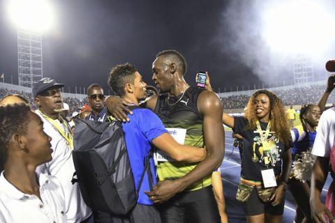 Jamaica's Usain Bolt, center right, embraces South African sprinter Wayde van Niekerk after winning the "Salute to a Legend" 100 meters during the Racers Grand Prix at the national stadium in Kingston, Jamaica, Saturday, June 10, 2017. Bolt started his final season with his last race on Jamaican soil and plans to retire from track and field after the 2017 London World Championships in August. (AP Photo/Bryan Cummings)