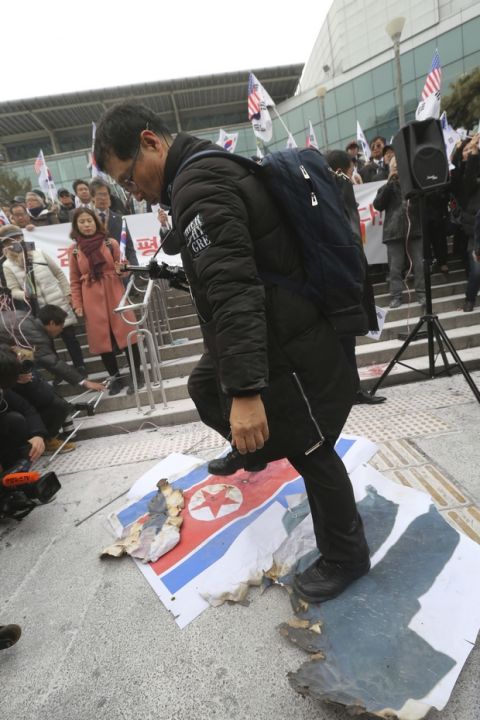 A South Korean protester walks on a defaced North Korean flag and portrait of North Korean leader Kim Jong Un during a rally against a visit of North Korean Hyon Song Wol, head of a North Korean art troupe, in front of Seoul Railway Station in Seoul, South Korea, Monday, Jan. 22, 2018. Dozens of conservative activists have attempted to burn a large photo of North Korean leader Kim Jong Un as the head of the North's hugely popular girl band passed by them at a Seoul railway station. (AP Photo/Ahn Young-joon)