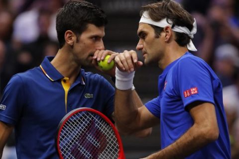 Team Europe's Roger Federer, right, whispers to Novak Djokovic during a men's doubles tennis match against Team World's Jack Sock and Kevin Anderson at the Laver Cup, Friday, Sept. 21, 2018, in Chicago. (AP Photo/Jim Young)