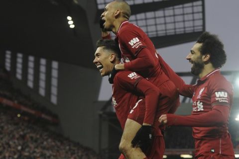 Liverpool's Roberto Firmino, left, celebrates with his teammate Liverpool's Fabinho, top, and Liverpool's Mohamed Salah, right, after scoring his side's second goal during the English Premier League soccer match between Liverpool and Crystal Palace at Anfield in Liverpool, England, Saturday, Jan. 19, 2019. (AP Photo/Rui Vieira)