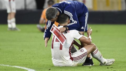 Olympiakos' Omar Elabdellaoui is consoled after the Europa League round of 16 second leg soccer match between Wolves and Olympiakos at Molineux Stadium in Wolverhampton, England, Thursday, Aug. 6, 2020. (AP Photo/Rui Vieira)