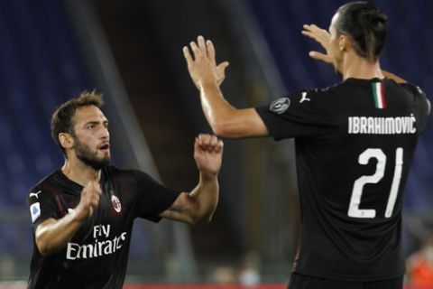 AC Milan's Hakan Calhanoglu, left, celebrates with his teammate Zlatan Ibrahimovic after scoring his side's opening goal during the Serie A soccer match between Lazio and AC Milan at the Rome Olympic stadium, Saturday, July 4, 2020. (AP Photo/Riccardo De Luca)