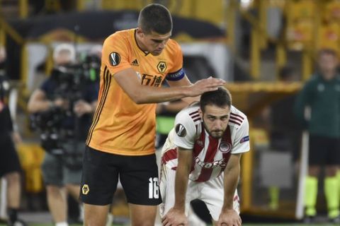 Wolverhampton Wanderers' Conor Coady, left, consoles Olympiakos' Kostas Fortounis after the Europa League round of 16 second leg soccer match between Wolves and Olympiakos at Molineux Stadium in Wolverhampton, England, Thursday, Aug. 6, 2020. (AP Photo/Rui Vieira)