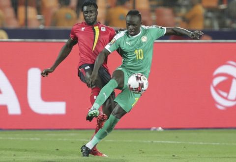Uganda's Bevis Kristofer Kizito Mugabi, left, and Senegal's Sadio Mane fight for the ball during the African Cup of Nations round of 16 soccer match between Uganda and Senegal in Cairo International stadium in Cairo, Egypt, Friday, July 5, 2019. (AP Photo/Hassan Ammar)
