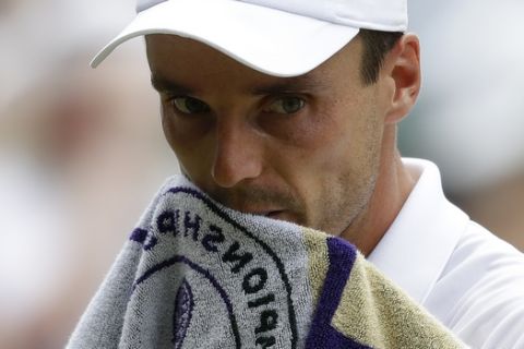 Spain's Roberto Bautista Agut wipes his face with a towel as he plays Serbia's Novak Djokovic in a Men's singles semifinal match on day eleven of the Wimbledon Tennis Championships in London, Friday, July 12, 2019. (AP Photo/Kirsty Wigglesworth)