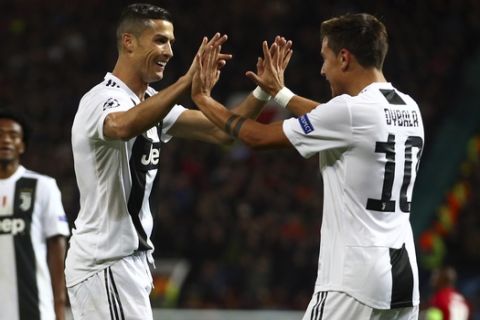 Juventus forward Paulo Dybala, right, celebrates with Juventus forward Cristiano Ronaldo after scoring the opening goal during the Champions League group H soccer match between Manchester United and Juventus at Old Trafford, Manchester, England, Tuesday, Oct. 23, 2018. (AP Photo/Dave Thompson)