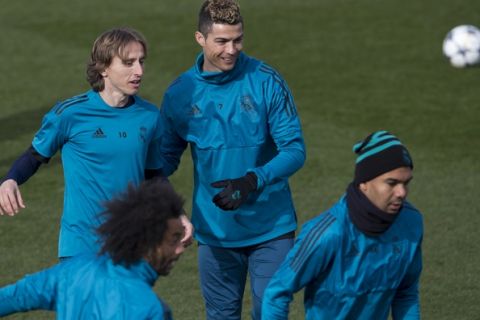 Real Madrid's Cristiano Ronaldo, center, smiles next to Luka Modric, left, during a training session in Madrid, Spain, Tuesday Feb. 13, 2018. Real Madrid will play Paris Saint Germain Wednesday in a Round of 16, 1st leg Champions League soccer match. (AP Photo/Paul White)