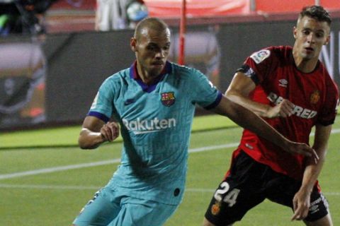 FC Barcelona's Martin Braithwaite, left, vies for the ball with Marllorca's Martin Valjent, right, during the Spanish La Liga soccer match between Mallorca and FC Barcelona at Son Moix Stadium in Palma de Mallorca, Spain, Saturday, June 13, 2020. With virtual crowds, daily matches and lots of testing for the coronavirus, soccer is coming back to Spain. The Spanish league resumes this week more than three months after it was suspended because of the COVID-19 pandemic. (AP Photo/Francisco Ubilla)