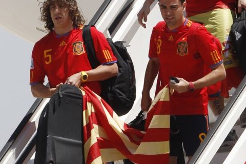 Spain's soccer player Xavi Hernandez (R) and Carles Puyol arrive at Madrid's Barajas airport holding a Catalonian flag July 12, 2010. Spain stunned the Netherlands to win their first World Cup on Sunday in sensational fashion with a goal in the last minutes of extra time.  REUTERS/Gustau Nacarino (SPAIN - Tags: SPORT SOCCER WORLD CUP)