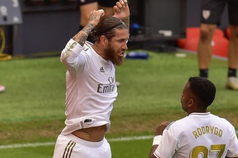 Real Madrid's Sergio Ramos, left, celebrates after scoring the opening goal from a penalty shoot during the Spanish La Liga soccer match between Athletic Club and Real Madrid at the San Manes stadium in Bilbao, Spain, Sunday, July 5, 2020. (AP Photo/Alvaro Barrientos)
