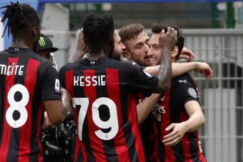AC Milan's Hakan Calhanoglu celebrates with teammates after scoring his side's opening goal during the Serie A soccer match between AC Milan and Sassuolo at the San Siro stadium, in Milan, Italy, Wednesday, April 21, 2021. (AP Photo/Antonio Calanni)