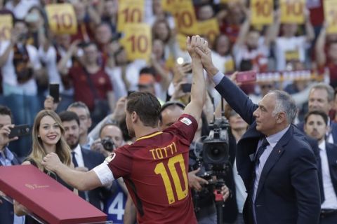 Roma president James Pallotta lifts the arm of Francesco Totti as he salutes his fans after an Italian Serie A soccer match between Roma and Genoa at the Olympic stadium in Rome, Sunday, May 28, 2017. Francesco Totti is playing his final match with Roma against Genoa after a 25-season career with his hometown club. (AP Photo/Alessandra Tarantino)
