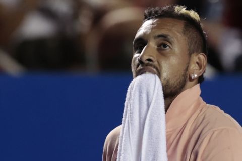 Australia's Nick Kyrgios carries a towel between his teeth during an opening-round match against France's Ugo Humbert at the Mexican Open tennis tournament in Acapulco, Mexico, Tuesday, Feb. 25, 2020. Kyrgios retired from the match following the first set. (AP Photo/Rebecca Blackwell)