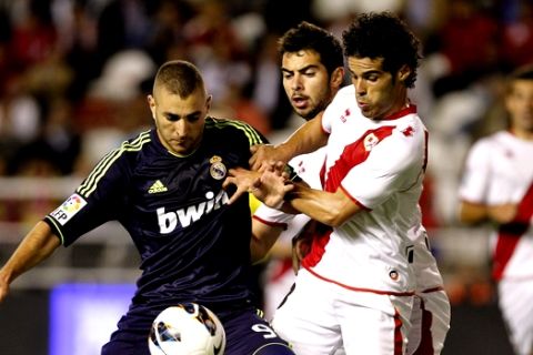 Real Madrid's Karim Benzema from France, left, vies for the ball with Rayo Vallecano's Jose Manuel Casado, right, during a Spanish La Liga soccer match at the Vallecas stadium in Madrid, Spain, Monday, Sept. 24, 2012. (AP Photo/Andres Kudacki)