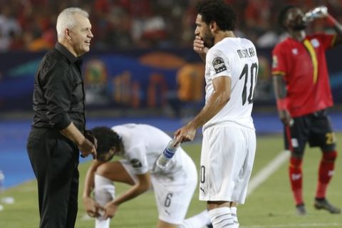 Egypt's head coach Javier Aguirre talks to Mohamed Salah during the African Cup of Nations group A soccer match between Egypt and Uganda in Cairo International Stadium in Cairo, Egypt, Sunday, June 30, 2019. (AP Photo/Ariel Schalit)
